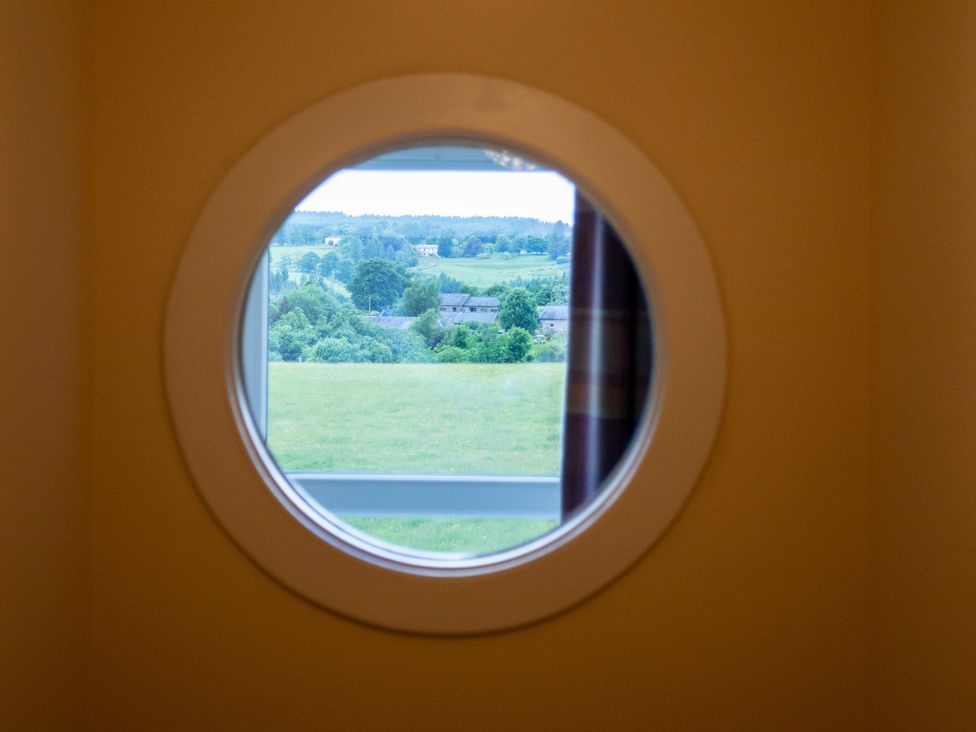 A round window showing a view of fields and trees at Gap Farm in Brampton
