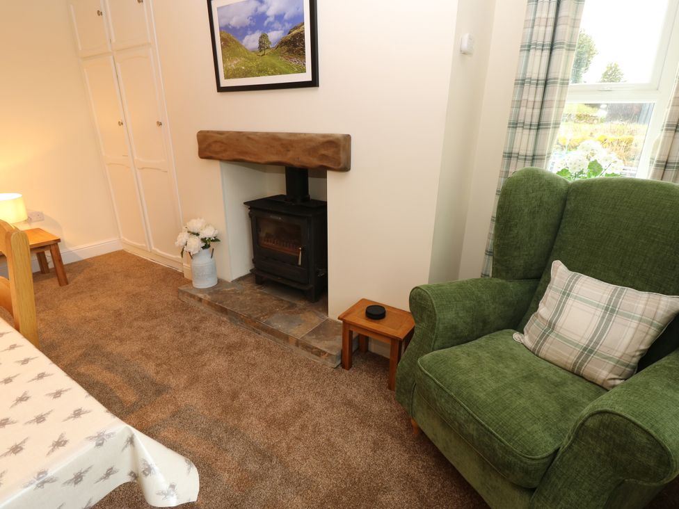 A living room with a fireplace and armchair at Gap Farm in Gilsland