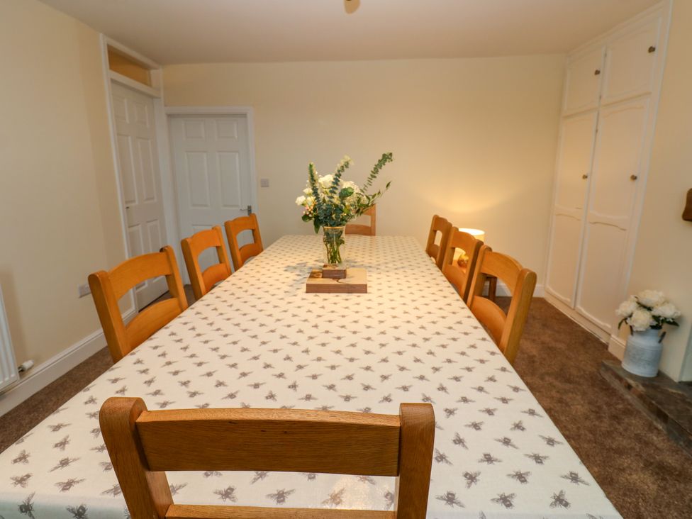 A dining room with a large table and a flower arrangement at Gap Farm in Gilsland
