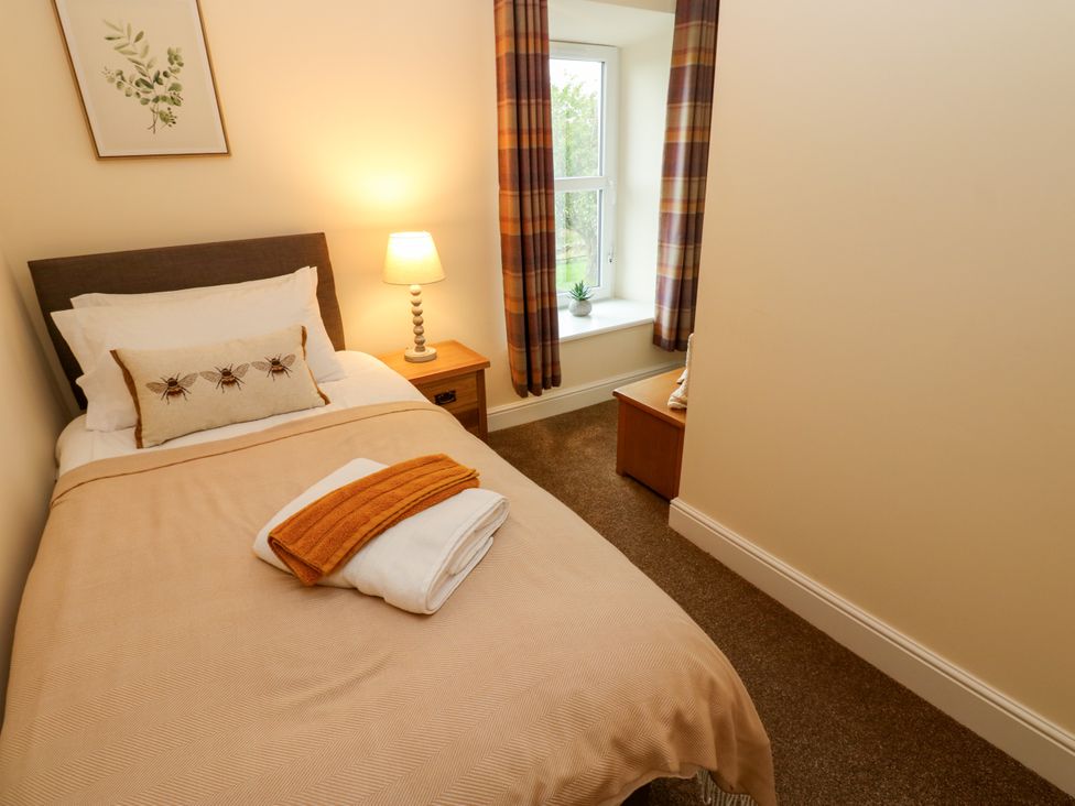 A bedroom with a bed and lamp at Gap Farm in Gilsland