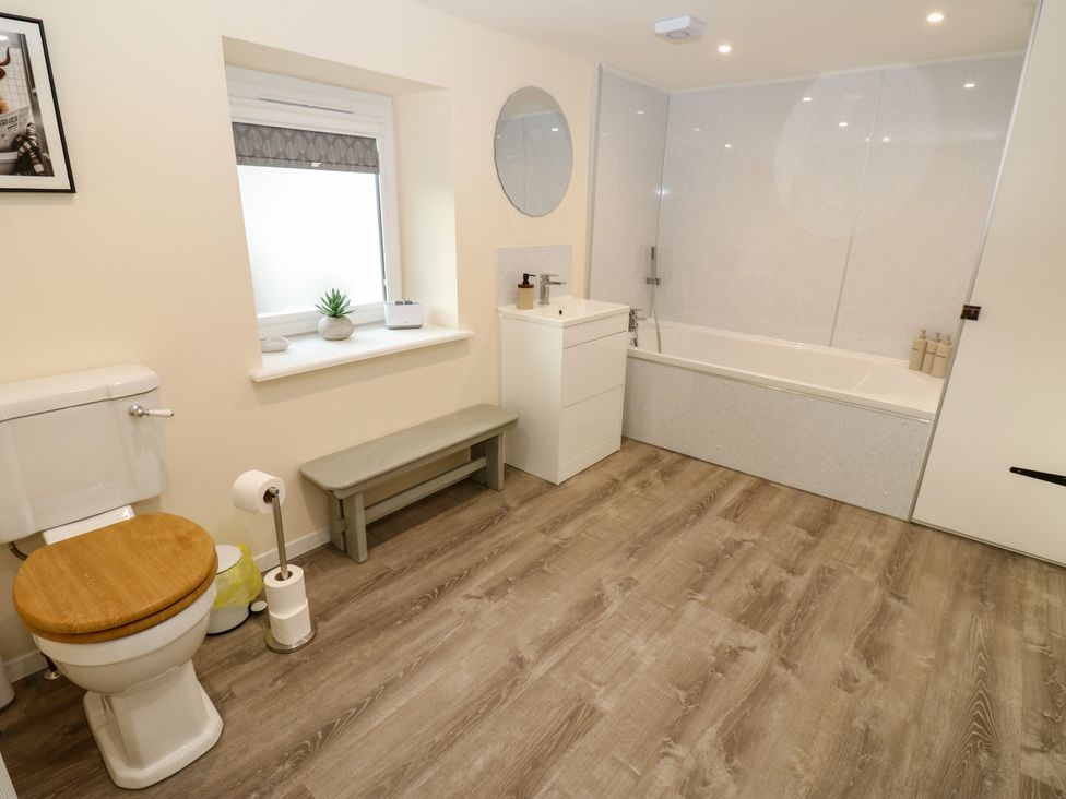 A bathroom featuring a toilet, sink, bath and mirror at Gap Farm in Gilsland