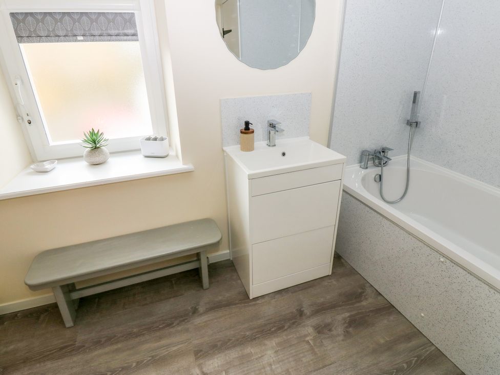 A bathroom with a bathtub and a vanity unit at Gap Farm in Gilsland