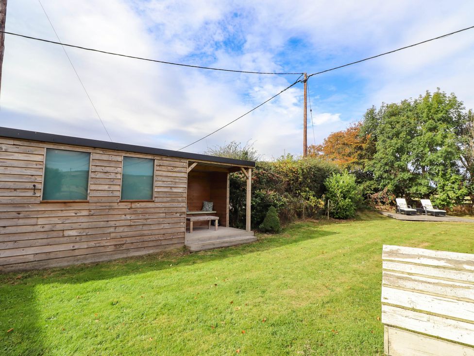 A wooden cabin with a table and chairs in an outdoor space at The Gables in Alnwick