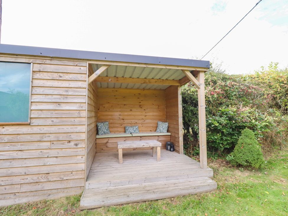 An outdoor seating area with a wooden cabin and bench at The Gables in Alnwick