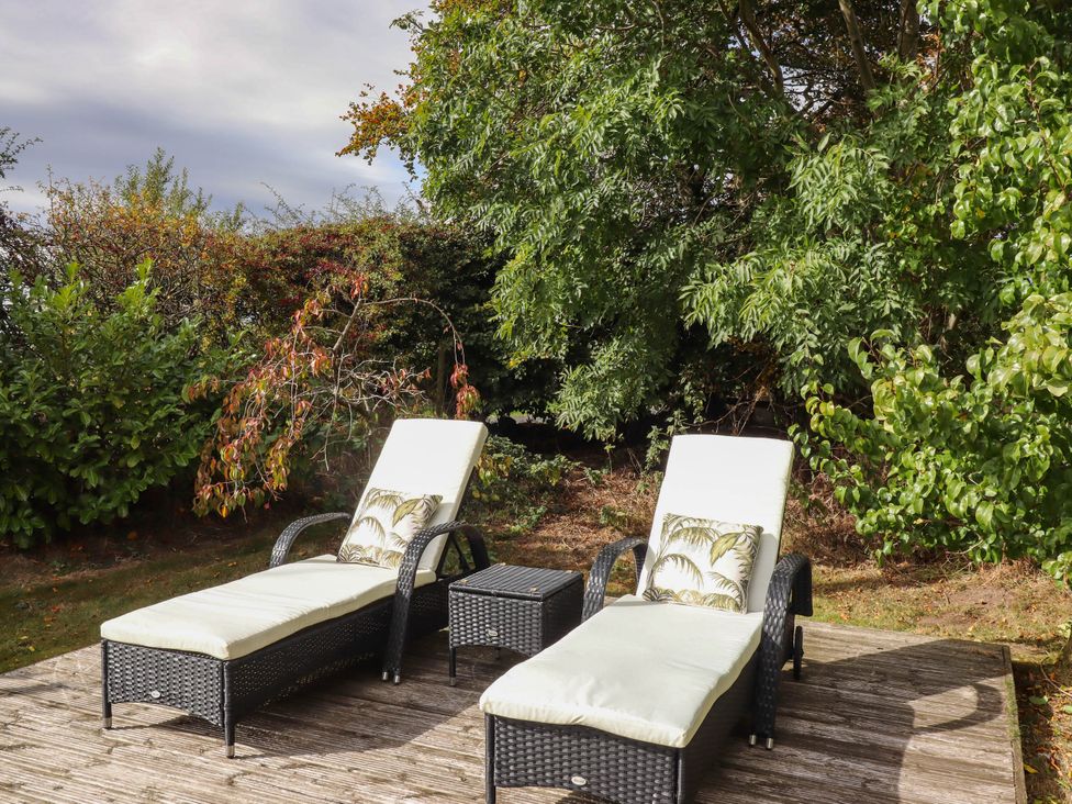 A deck area with lounge chairs and a table at The Gables in Alnwick