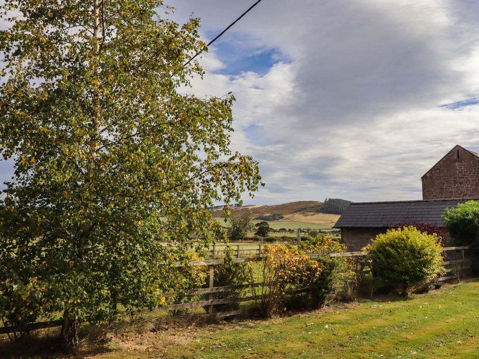A view of trees and hills with a building in the background at The Gables in Alnwick