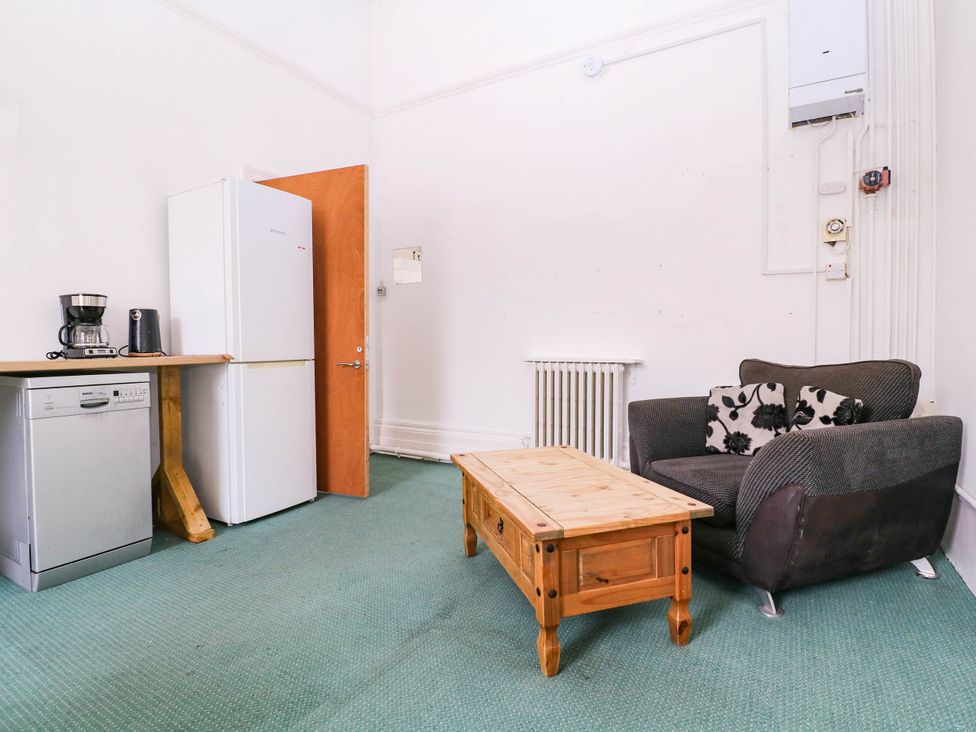 A living room with a refrigerator, coffee maker, dishwasher, sofa, and coffee table at 6 Caxton Place Newport, South Wales