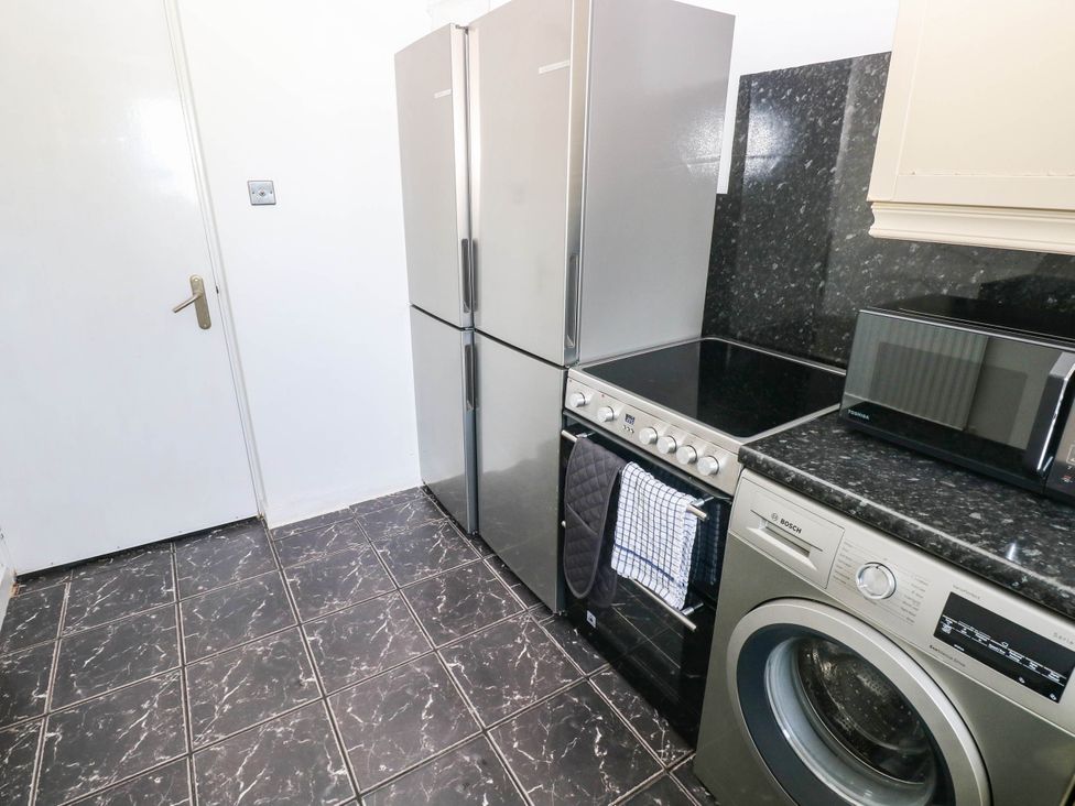 A kitchen with a refrigerator, oven, microwave, and washing machine at 21 Ferrara Square Swansea