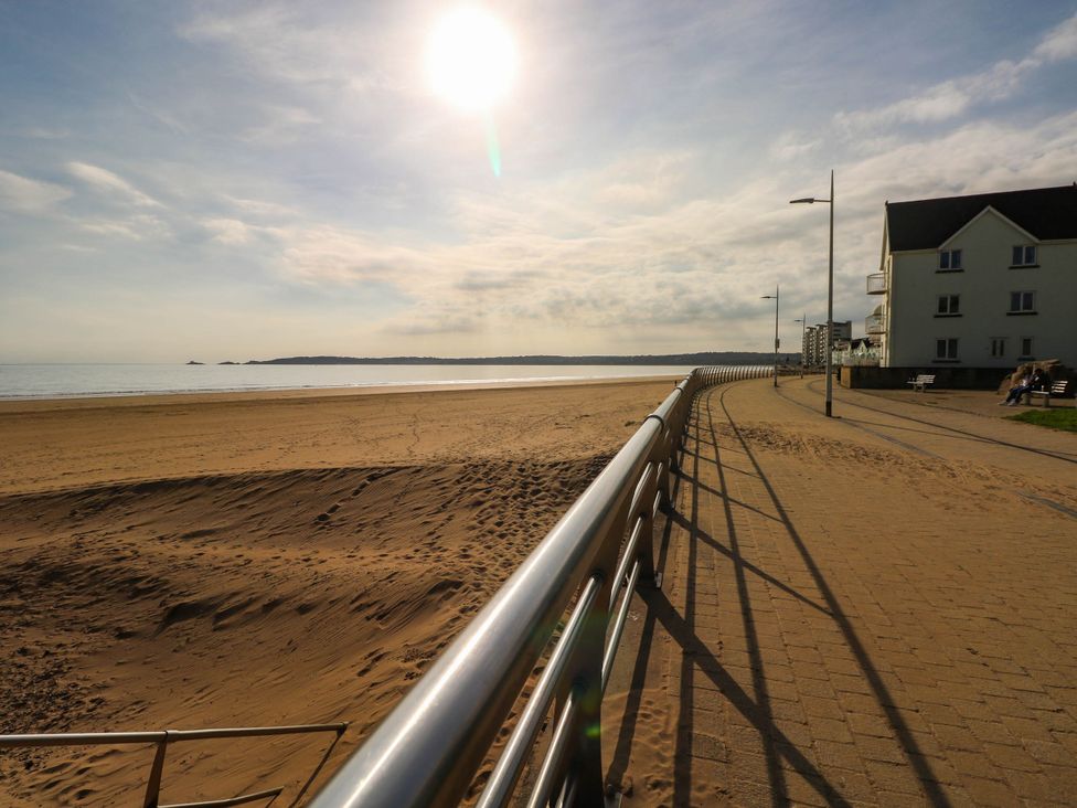 A beach with a walkway and a building at 21 Ferrara Square in Swansea