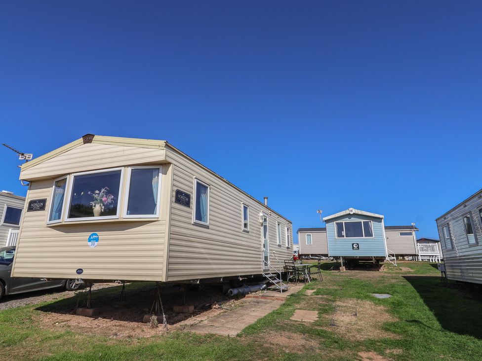 A row of static caravans on a grassy area at Spruces 30 Sandy Bay, Exmouth