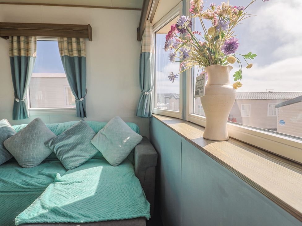 A living room with a sofa and a flower vase at Spruces 30 Sandy Bay, Exmouth