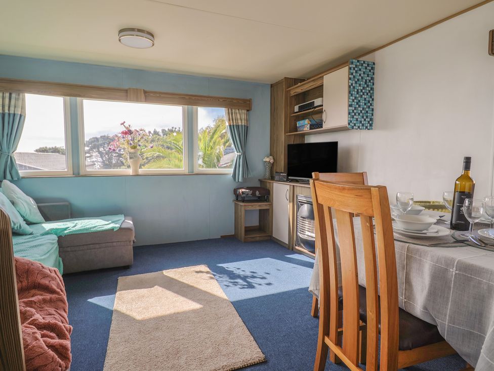 A living room with couch, dining table, and television at Spruces 30, Sandy Bay, Exmouth