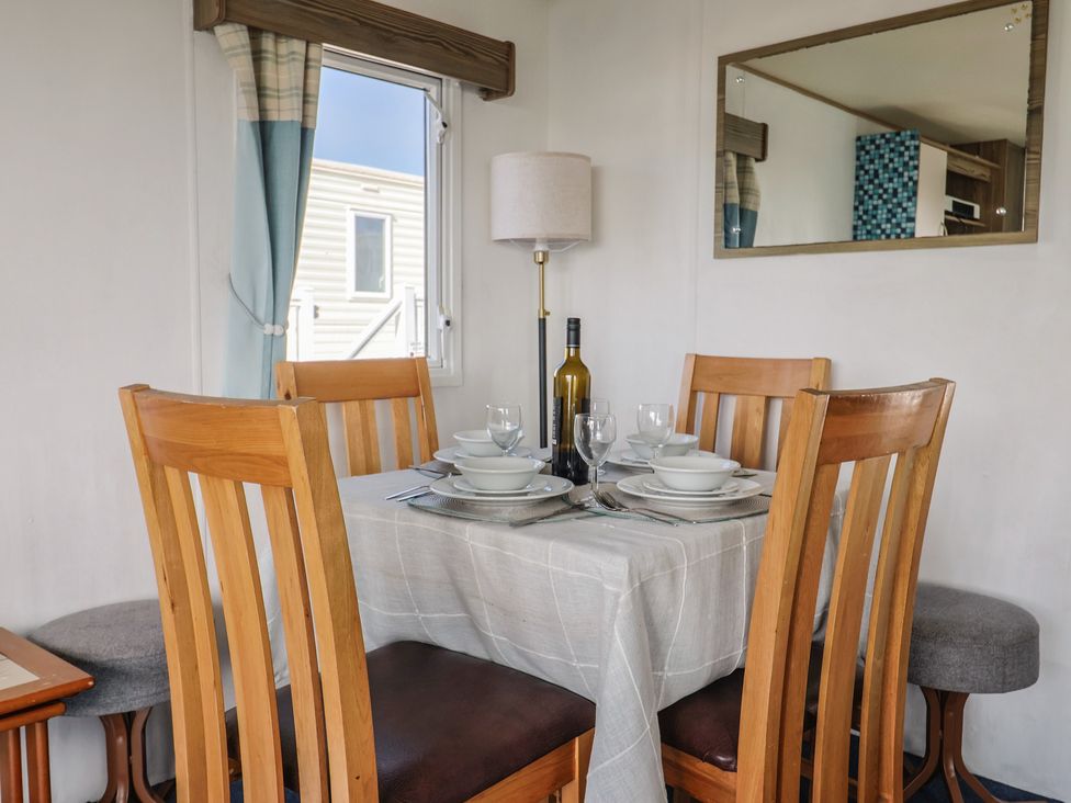 A dining table set with dishes and a wine bottle at Spruces 30, Sandy Bay, Exmouth