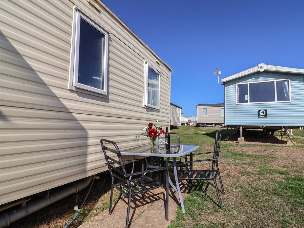 An outdoor table with chairs and flowers near trailers at Spruces 30 Sandy Bay, Exmouth