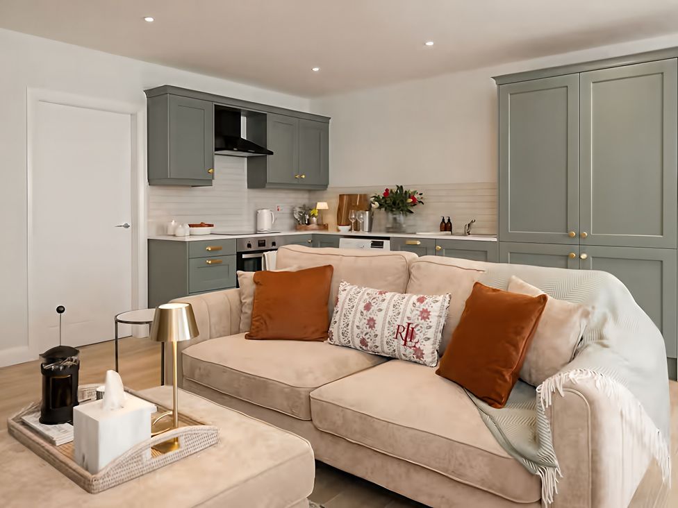 A living room with a sofa and kitchen in Long Meadow Apartment in Portglenone