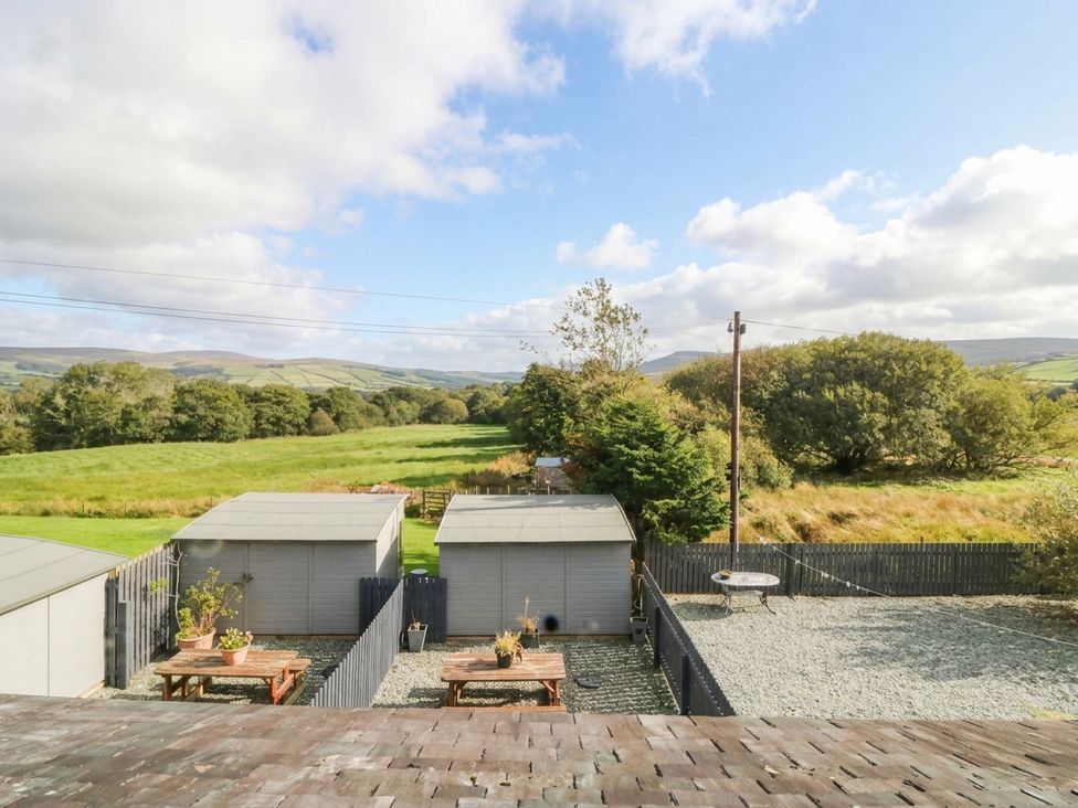 A garden with sheds and tables at Holly in Cleator