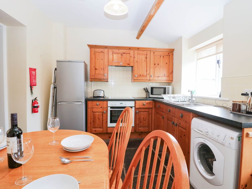 A kitchen with wooden cabinets and appliances at Holly in Cleator