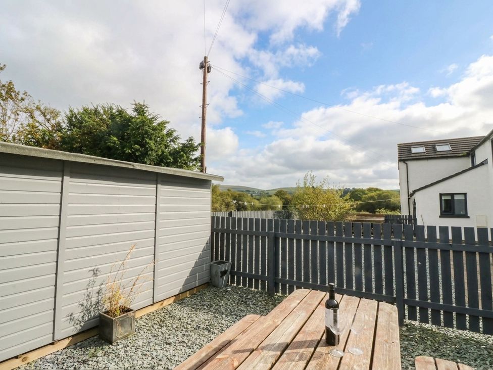 A garden with a wooden table and a shed at Holly in Cleator