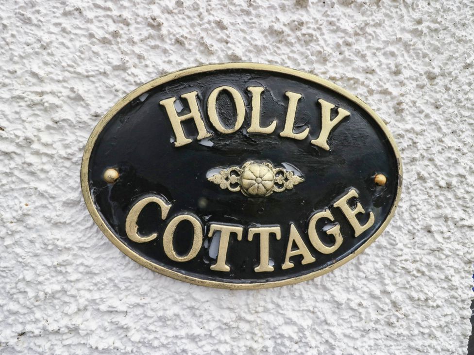 A nameplate displaying 'Holly Cottage' on a wall at Holly in Cleator