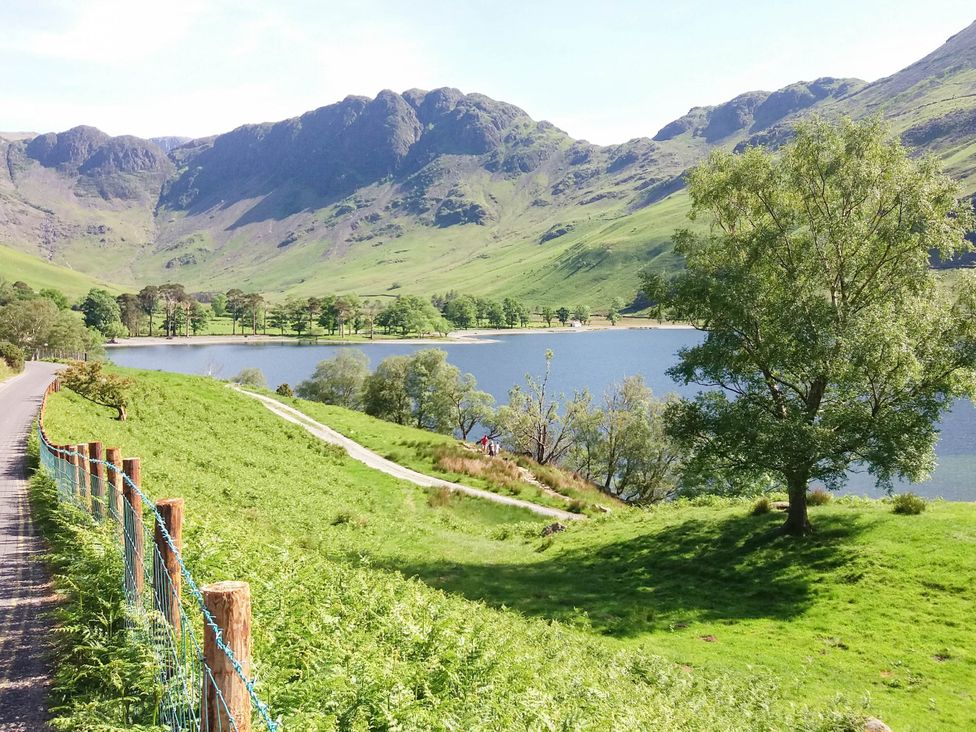 A path alongside a lake with mountains and trees at Holly in Cleator