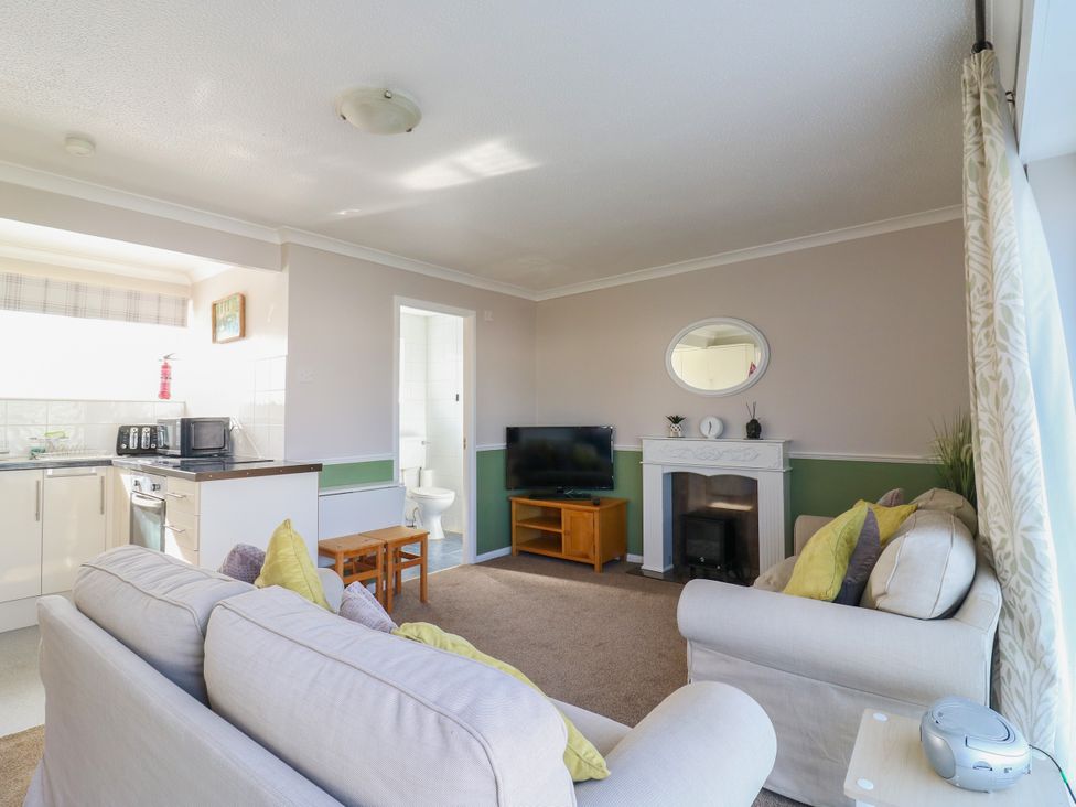 A living room with a sofa and television at 110 Bay View in New Romney