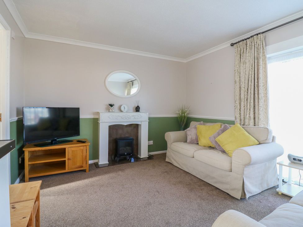 A living room with a sofa and TV at 110 Bay View in New Romney
