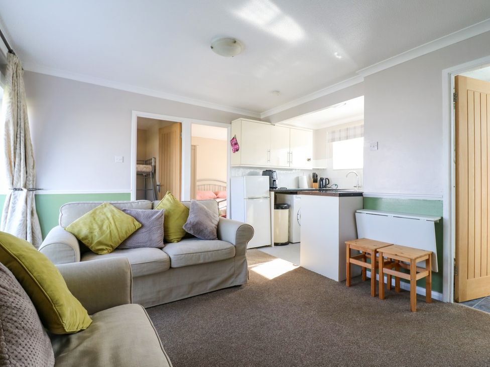 A living room with a sofa and kitchen unit at 110 Bay View in New Romney