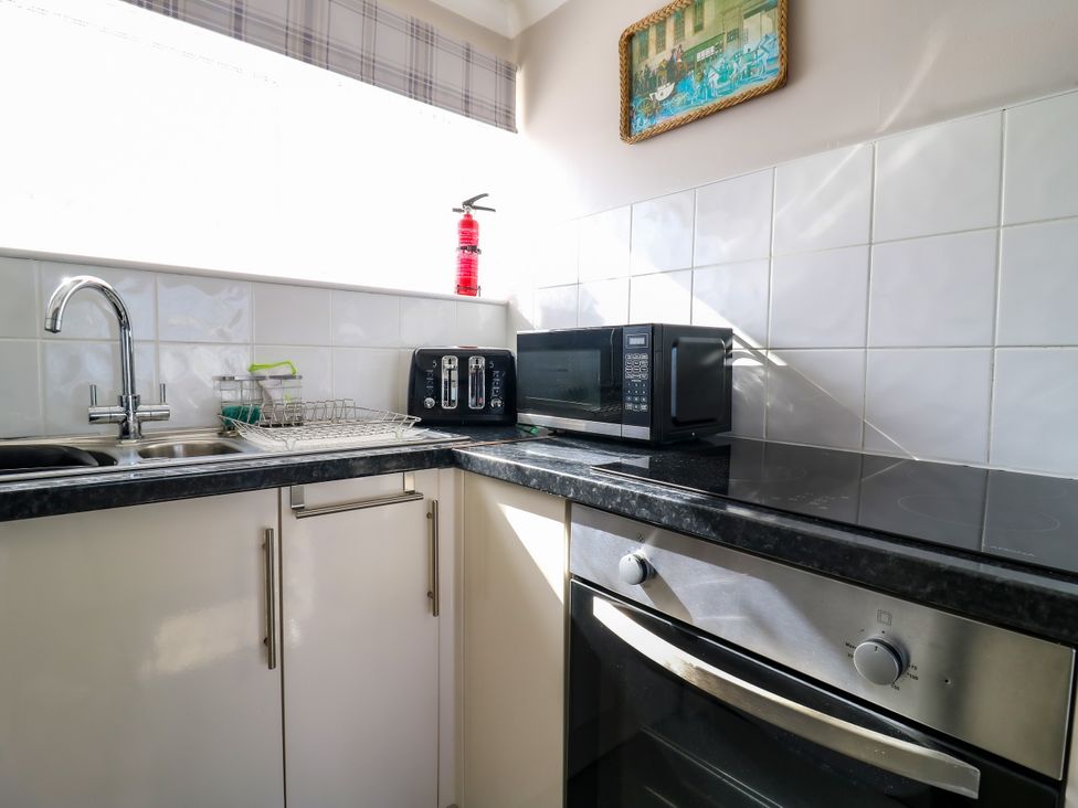 A kitchen with sink, toaster, and microwave at 110 Bay View in New Romney