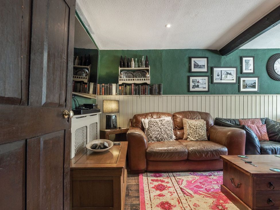 A living room with a leather sofa and bookshelves at The Half Boar in Bishop's Castle