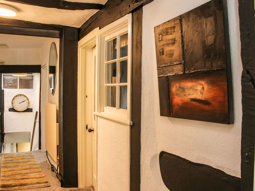 A hallway with a clock, mirror, and artwork at The Half Boar in Bishop's Castle