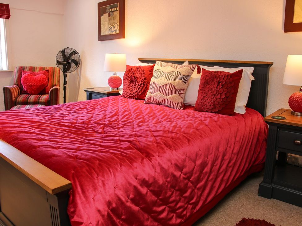 A bedroom with a red bedspread and decorative pillows at The Half Boar in Bishop's Castle