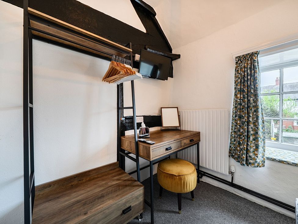 A bedroom with a clothes rack and desk at The Half Boar in Bishop's Castle