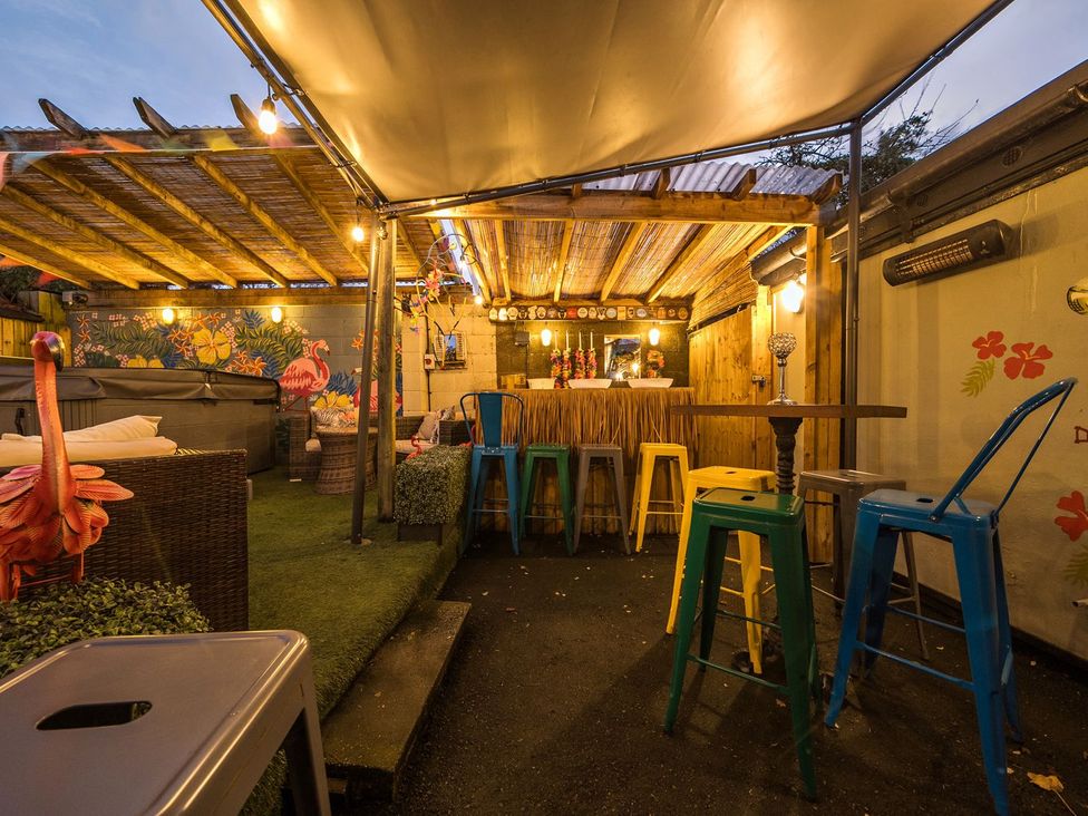 An outdoor bar area with stools and a hot tub at The Half Boar in Bishop's Castle