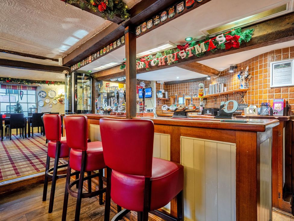 A bar area with stools and decorations at The Half Boar in Bishop's Castle