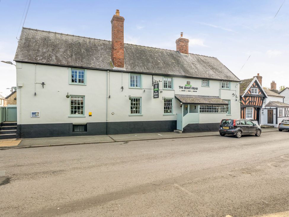 A pub with signage and parked cars at The Boar's Head in Bishop's Castle