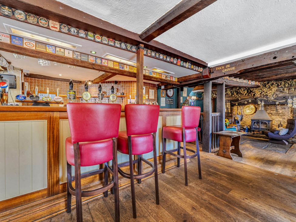 A bar with stools and a fireplace at The Half Boar in Bishop's Castle