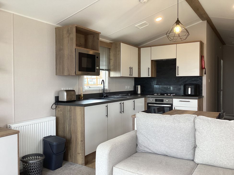 A kitchen with cabinets, a stove, microwave and sofa at Club Sahara, Sandy Bay, Exmouth