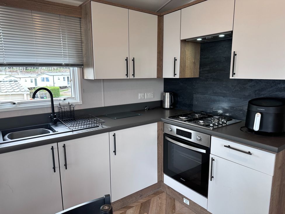 A kitchen with a stove, oven, sink, and air fryer at Club Sahara in Sandy Bay, Exmouth
