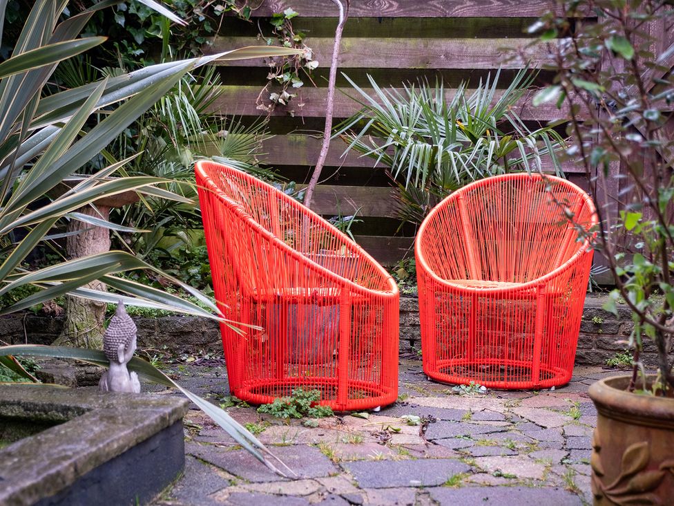 Two red chairs and a buddha statue in a garden with plants at Gorgeous 2Bed Apartment with Patio, Brighton And Hove
