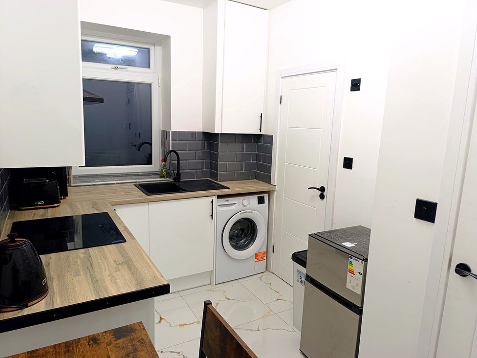 A kitchen with a sink and washing machine at Cardiff Cozy One Bedroom Apartment in Cardiff