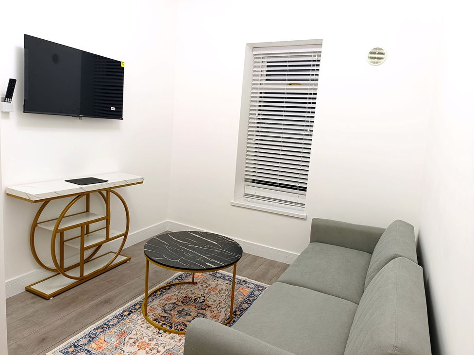 A living room with a sofa, coffee table, and television at Cardiff Cozy One Bedroom Apartment in Cardiff