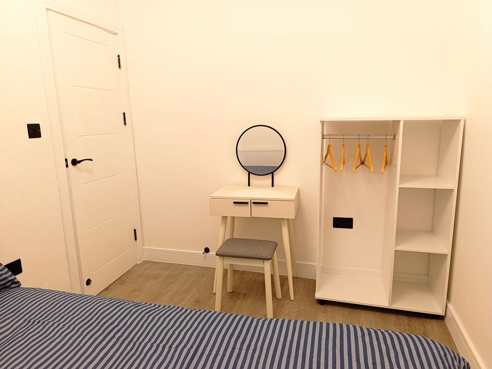 A bedroom with bed, vanity, mirror, chair, and wardrobe at Cardiff Cozy One Bedroom Apartment, Cardiff