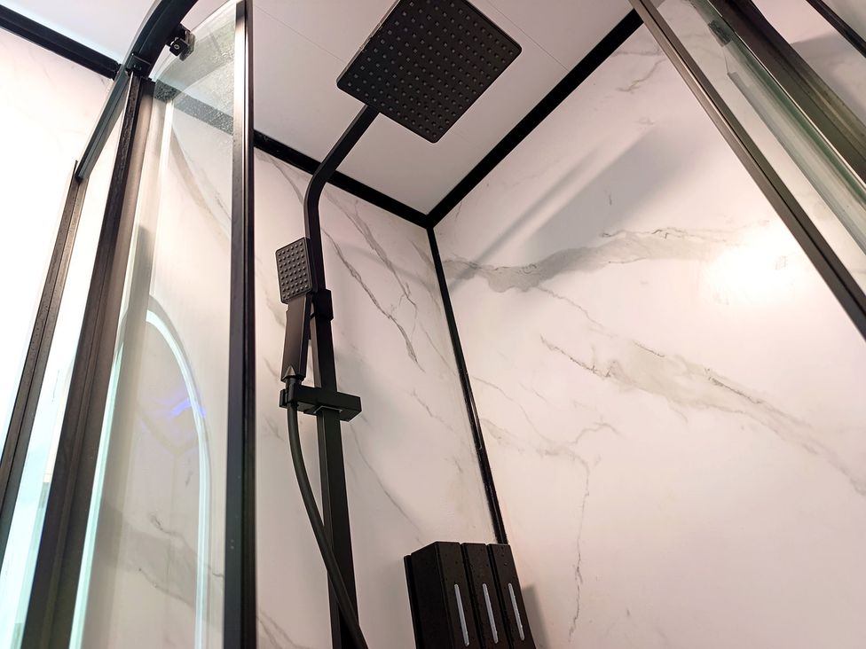 A shower with a black showerhead and glass doors at Cardiff Cozy One Bedroom Apartment in Cardiff