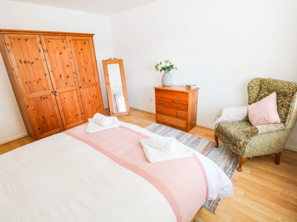 A bedroom with a wardrobe, mirror, chair, and bed at 24 Little Castle Grove in Hubberston