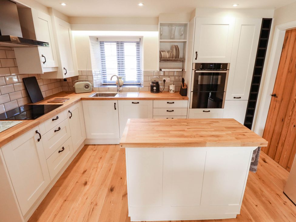 A kitchen with cabinets, sink, oven, and countertop at Three Chimneys in Scampton near Ingham