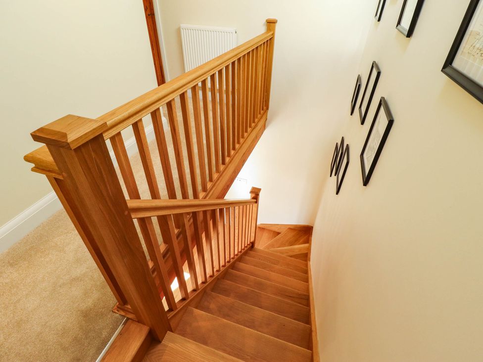 A staircase with wooden railing and picture frames at Three Chimneys Scampton near Ingham