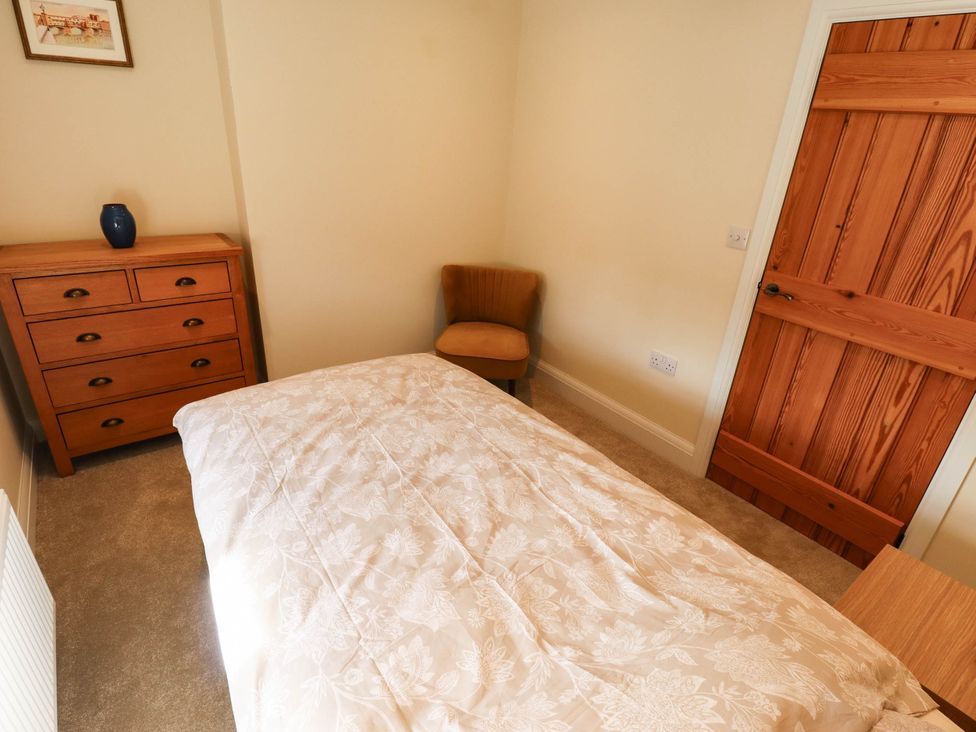 A bedroom with a bed, drawer, chair, and vase at Three Chimneys in Scampton near Ingham