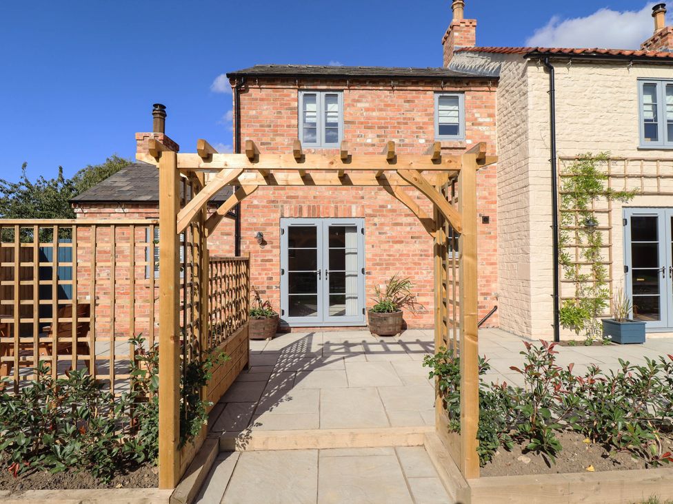 A garden with a wooden pergola and flower pots at Three Chimneys in Scampton near Ingham