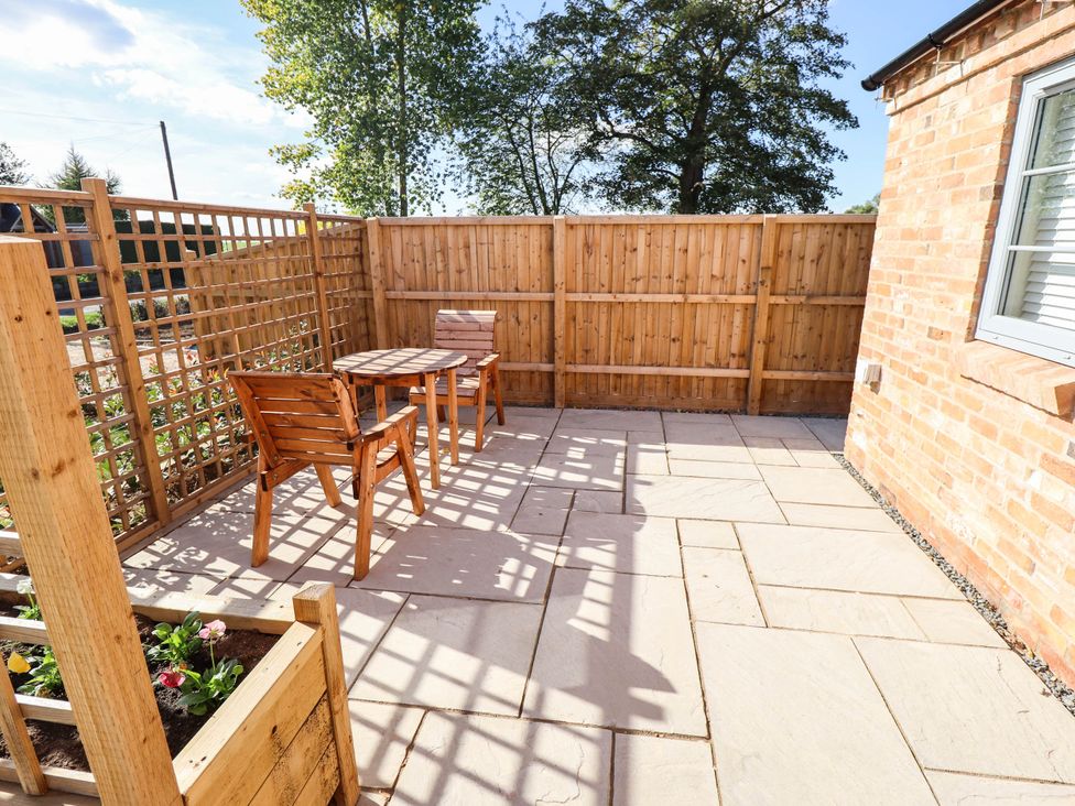 An outdoor space with a wood table and chairs at Three Chimneys in Scampton near Ingham
