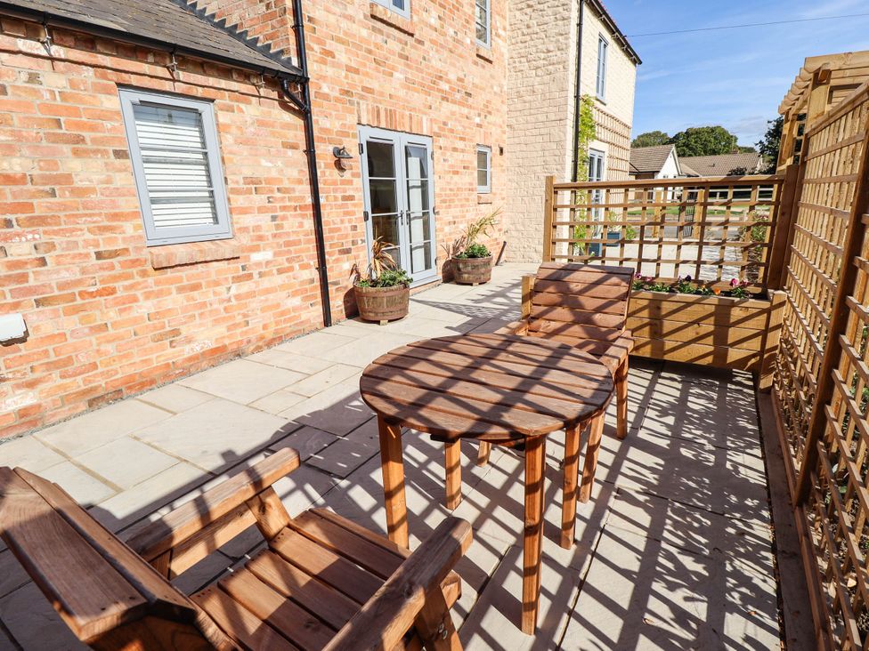 An outdoor area with a wooden table and chairs at Three Chimneys Scampton near Ingham